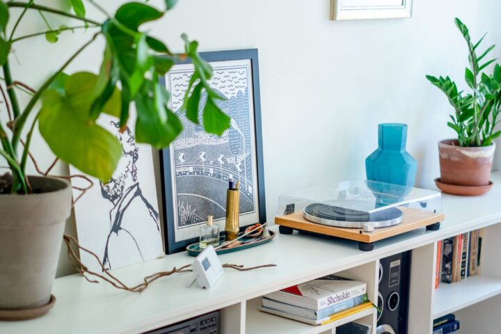 Platenspeler op een witte lage tafel met lp's en stereoapparatuur in de vakken eronder