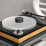 Moderne hifi-platenspeler met houten basis en transparant plateau