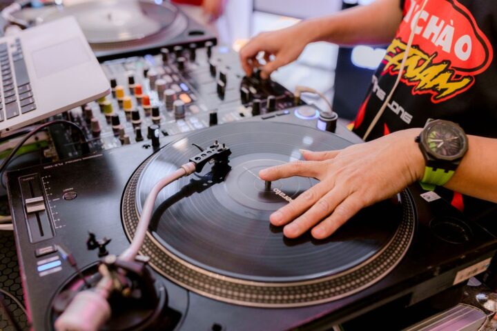 DJ met zijn hand op een plaat op een direct drive draaitafel naast een mixer